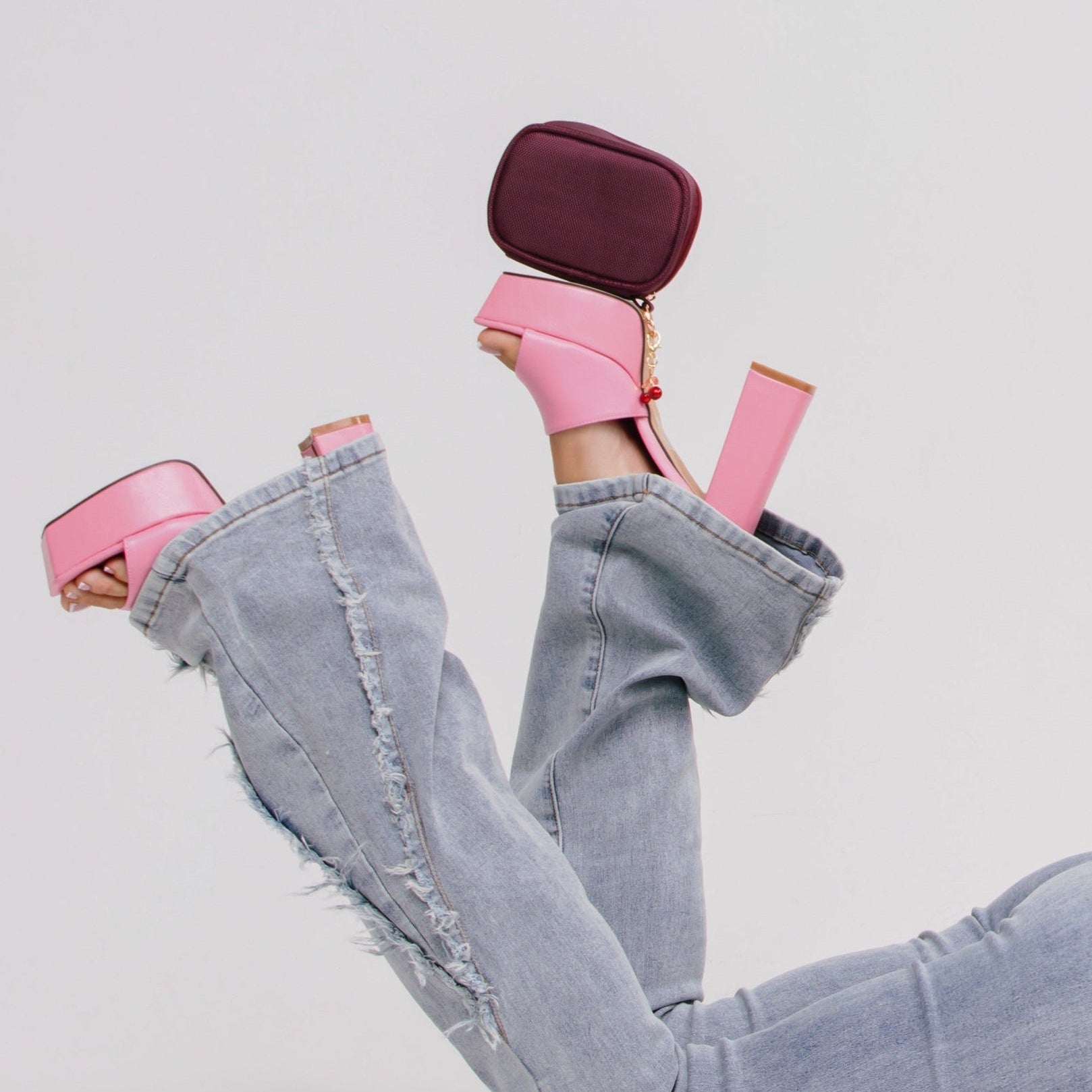 Pink high-heeled shoes with a matching handbag on a light gray background